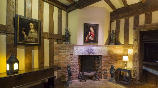 The Inner Hall with four garden statues surrounding the brick fireplace at Packwood House, Warwickshire